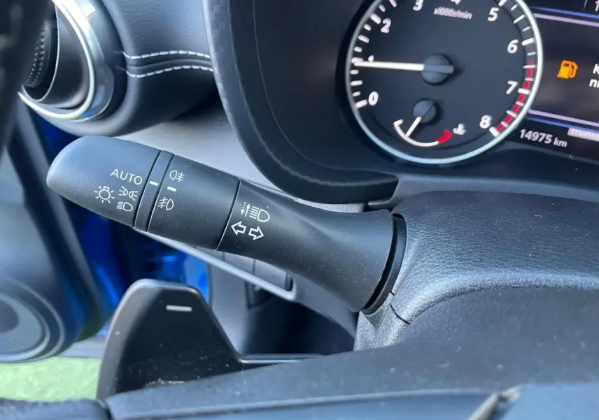 Gros plan sur la manette des feux et clignotants côté gauche du tableau de bord bleu magnetic du Nissan Juke 2024.