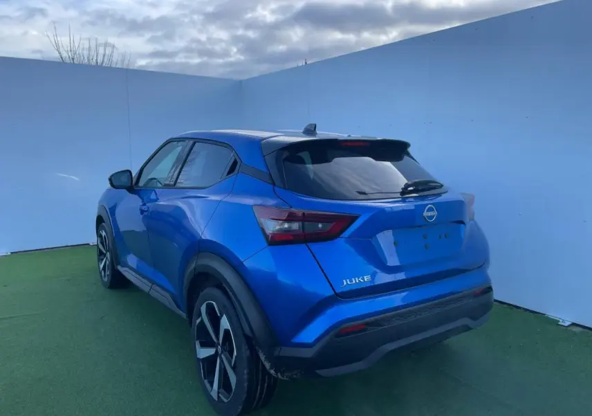 Vue 3/4 arrière gauche du Nissan Juke 2024 bleu magnetic avec toit noir et jantes alliage noires.