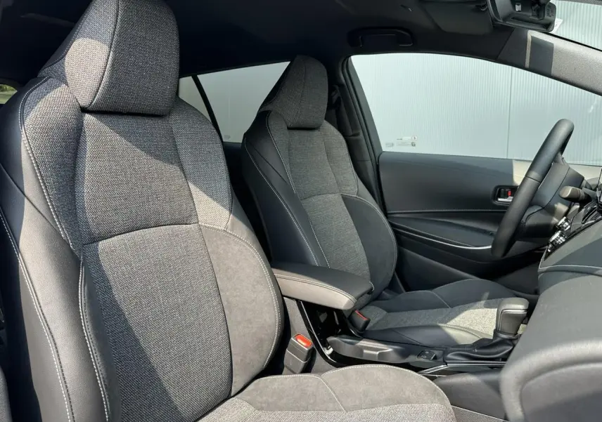Intérieur de la Toyota Corolla Touring Sport 2025, vue côté droit sur sièges tissu gris et accoudoir central noir.