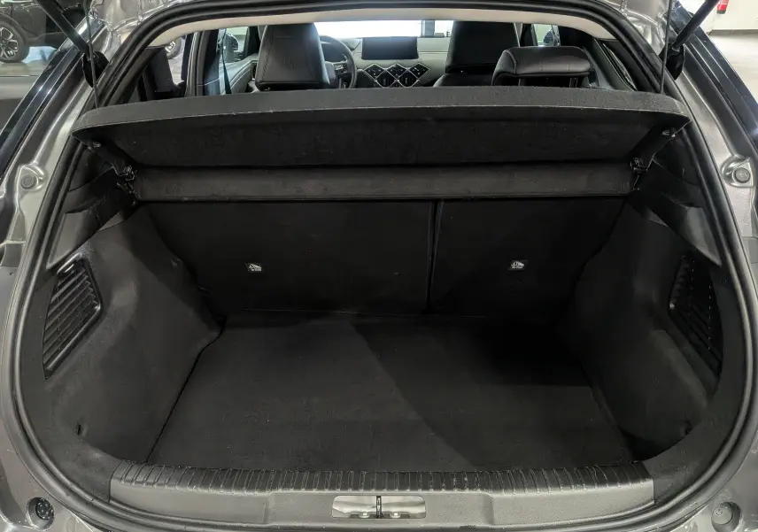 Coffre ouvert vu de l'arrière d'une DS3 2024 gris Platinium, intérieur noir avec tablette cache-bagages relevée.