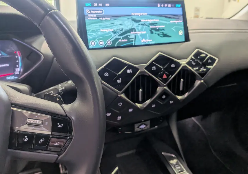 Vue intérieure du tableau de bord du DS3 2024 avec écran tactile GPS et commandes tactiles géométriques sur fond cuir noir.