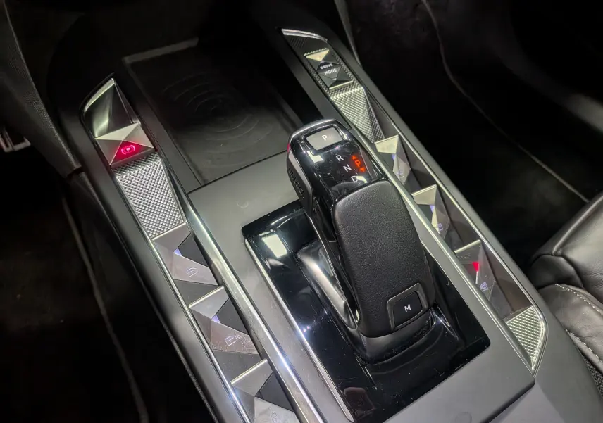 Le levier de vitesses noir brillant de la DS3 2024 en gros plan, entouré de boutons triangulaires chromés.