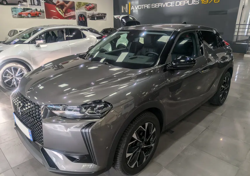 DS3 gris Platinium en 3/4 avant droit, soulignant sa calandre distinctive et ses jantes noires bicolores.