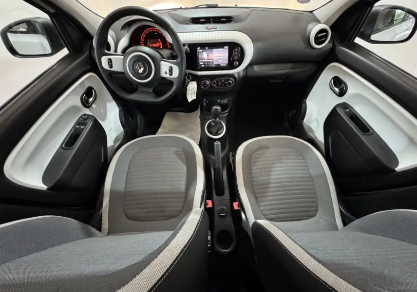 Intérieur avant de la Renault Twingo blanc et gris, vue centrée sur le tableau de bord et les sièges avant.
