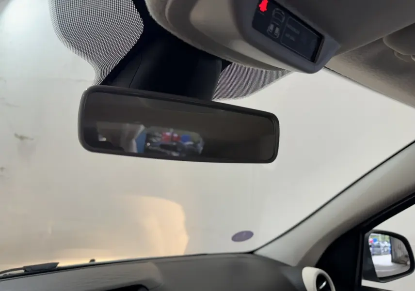 Vue intérieure du rétroviseur central d'une Renault Twingo blanche 2022, avec tableau de bord noir et rétro extérieur visible.