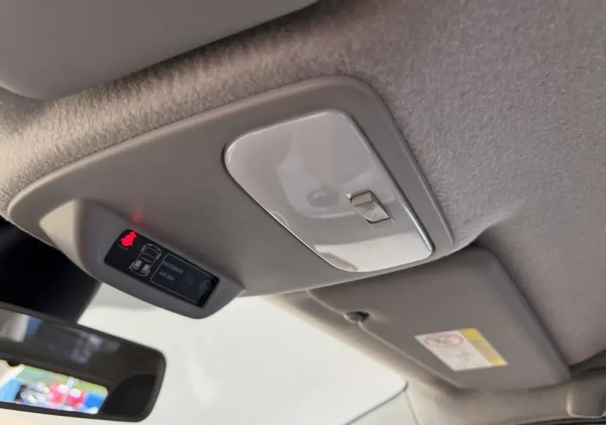 Vue intérieure rapprochée du plafonnier et du témoin d'airbag passager allumé dans une Renault Twingo blanche 2022.