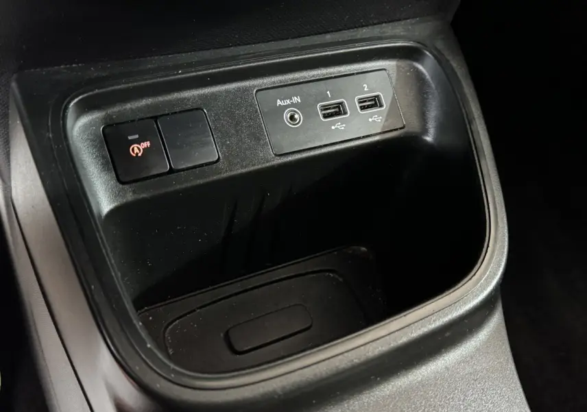 Gros plan sur la console centrale noire de la Renault Twingo blanche, montrant ports USB et bouton de désactivation start-stop.