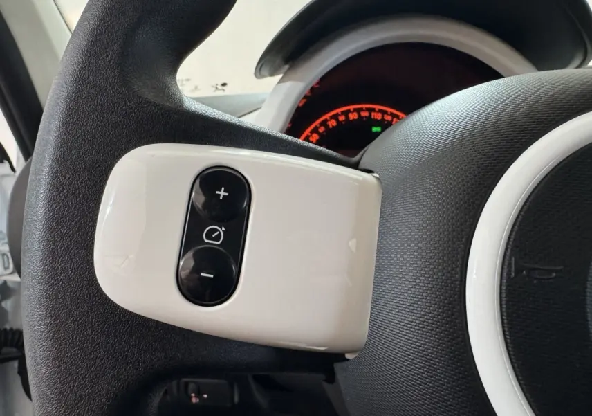 Gros plan sur les commandes blanches du régulateur de vitesse au volant d'une Renault Twingo blanche 2022.
