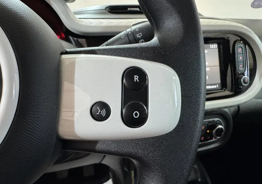 Gros plan sur la partie gauche du volant noir et blanc de la Renault Twingo 2022 avec commandes vocales et régulateur.