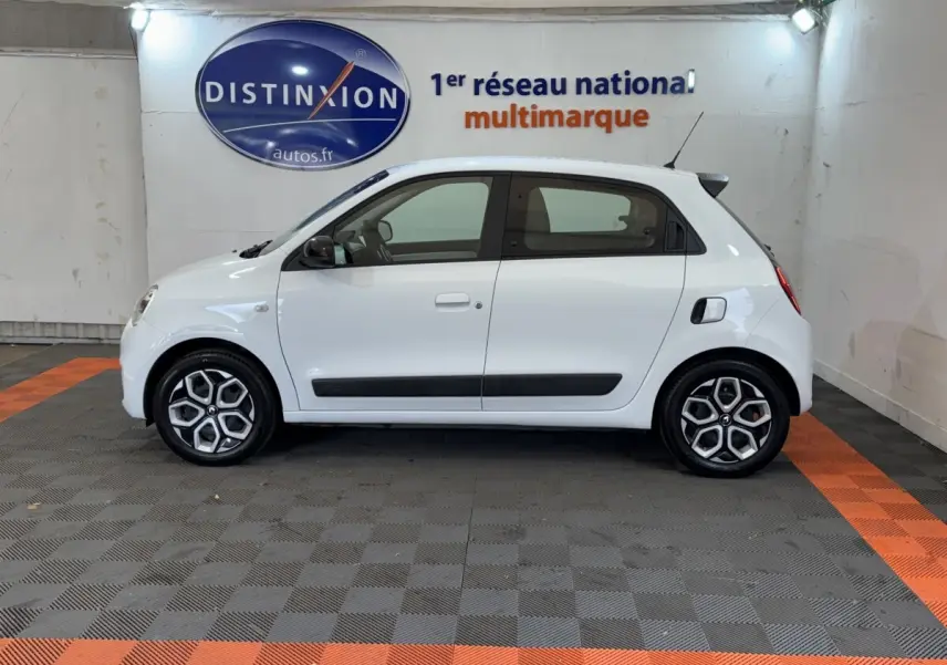Profil droit d'une Renault Twingo Equilibre blanche 2022, avec jantes distinctives et rétroviseurs noirs dans un showroom.
