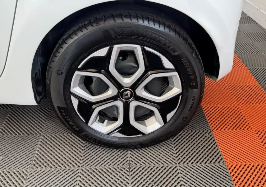 Gros plan sur la roue avant droite blanche d'une Renault Twingo 2022 avec jante noire et argentée au design hexagonal.