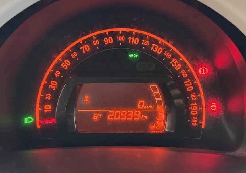 Gros plan sur le tableau de bord numérique éclairé en rouge de la Renault Twingo blanche, affichant 20939 km et 8°C.