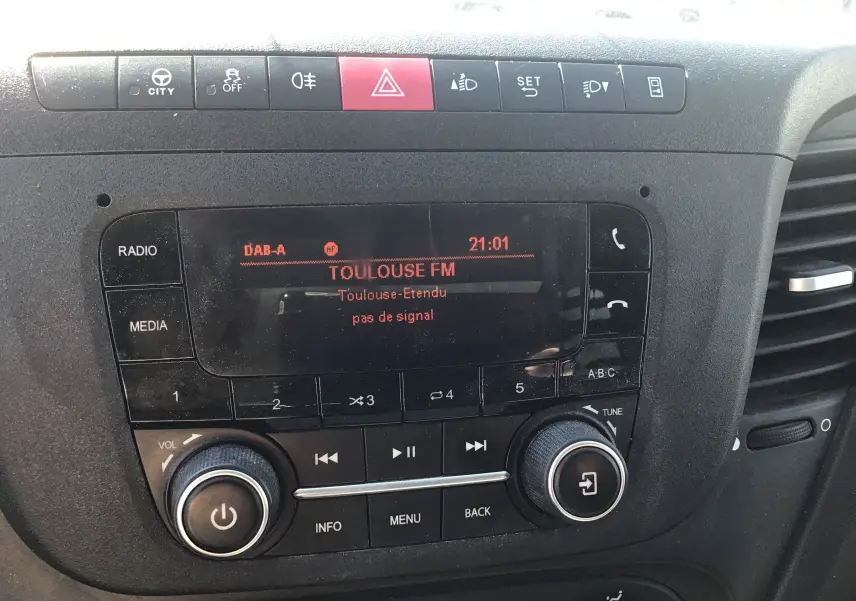 Gros plan sur la console centrale noire de l’Iveco Daily 2022, affichant la radio Toulouse FM en mode DAB-A.