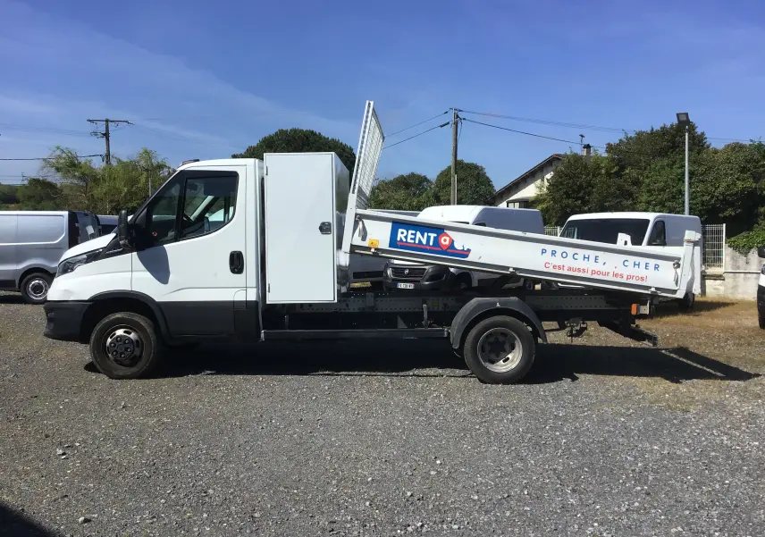 Vue latérale gauche d’un Iveco Daily blanc 35C14 avec benne basculante JPM en acier et coffre latéral fermé.