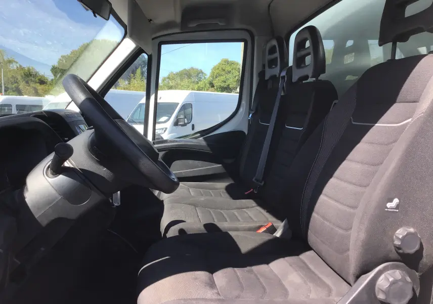 Vue intérieure côté conducteur de l'Iveco Daily Chassis Cabine 35C14 blanc, montrant les sièges noirs et le volant.