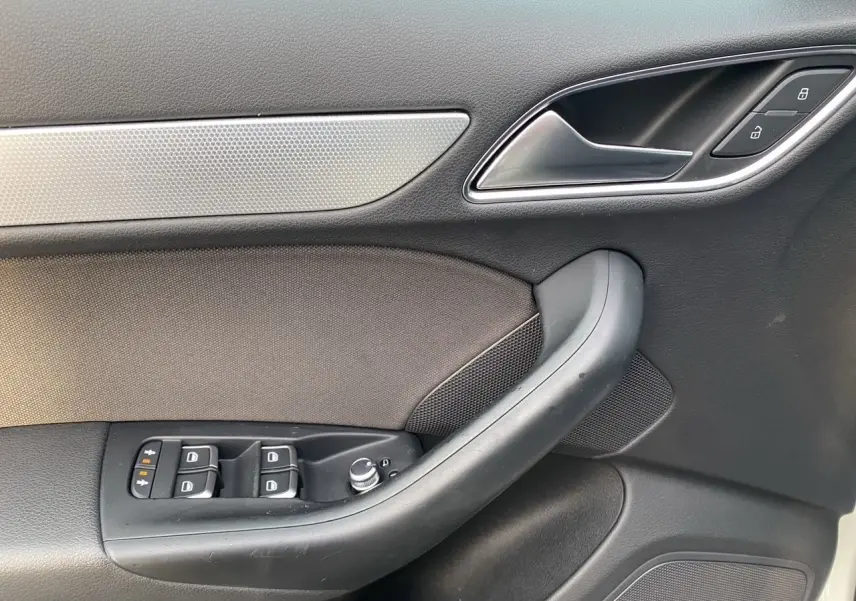Détail de la porte avant gauche noire avec commandes de vitres et verrouillage sur Audi Q3 blanc 2014.
