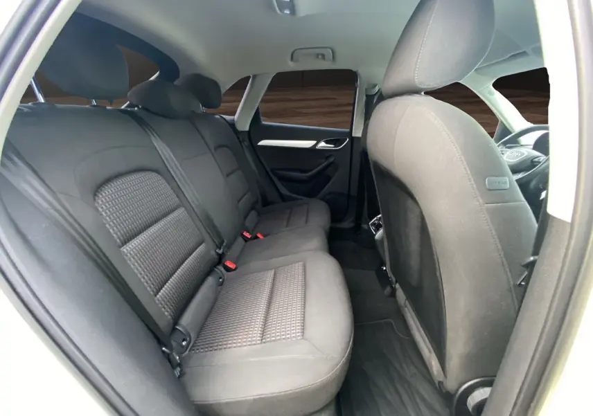 Vue intérieure arrière droite de l’Audi Q3 blanc 2014, sièges tissu noir avec vitres arrière surteintées.