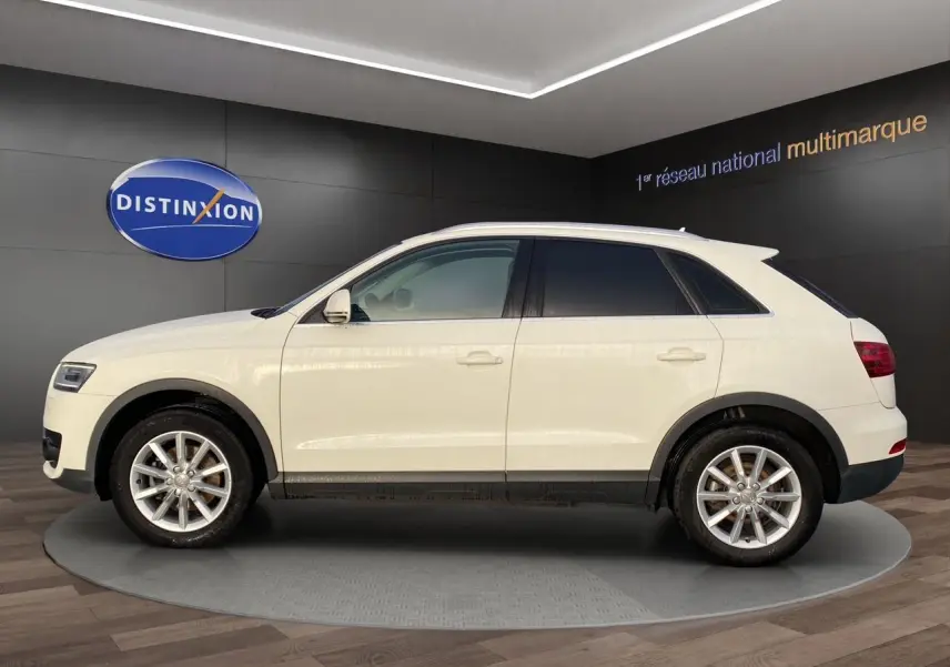Audi Q3 blanc vue de profil côté gauche avec vitres arrière surteintées dans un showroom.