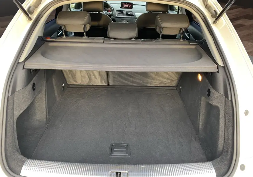 Coffre ouvert vu de l'arrière d'un Audi Q3 blanc 2014 avec cache-bagages et intérieur noir.