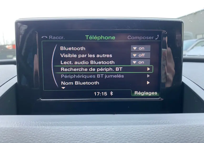 Écran GPS central affichant le menu Bluetooth dans l'habitacle d'un Audi Q3 blanc, vue de face.