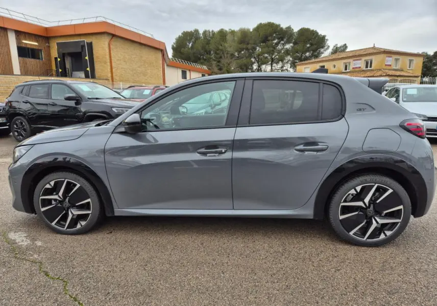Profil côté gauche d'une Peugeot 208 Hybrid 110 e-DCS6 GT gris avec jantes alliage 17 pouces et antenne requin.