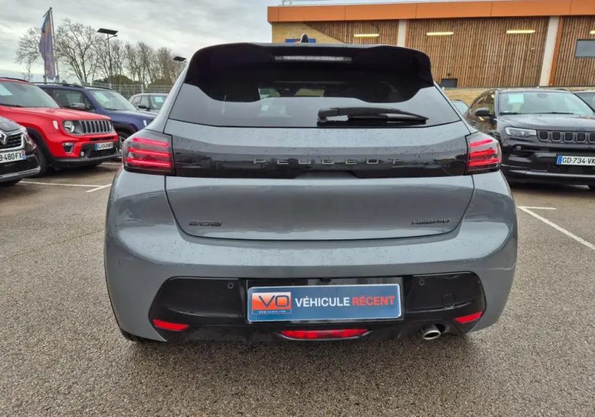 Vue arrière d'une Peugeot 208 Hybrid 110 gris, avec feux LED allumés et logo Peugeot visible sur le hayon.