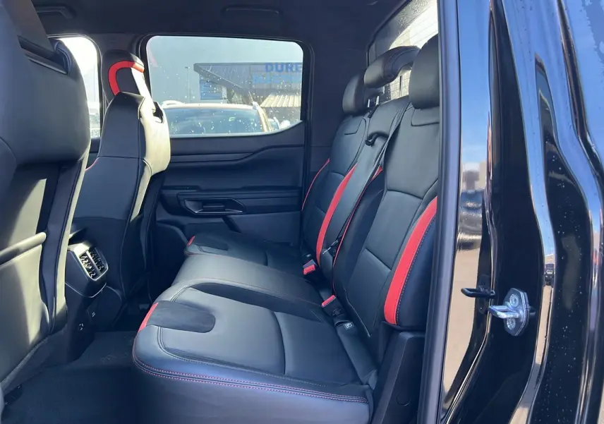Vue intérieure côté droit sur les sièges arrière noirs avec surpiqûres rouges du Ford Ranger Raptor 2025 noir absolu.