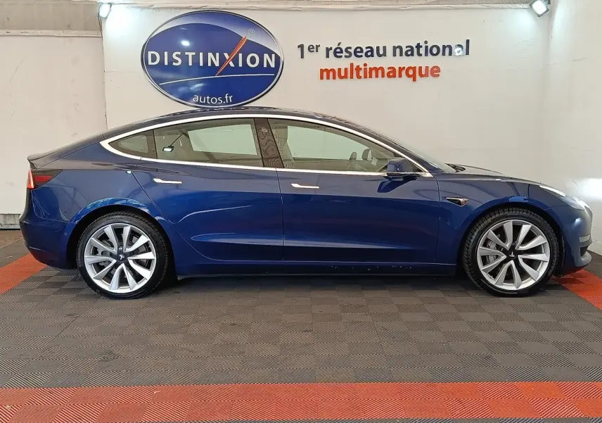 Profil latéral droit d'une Tesla Model 3 Long Range bleu électrique, avec jantes alliage et poignées affleurantes.