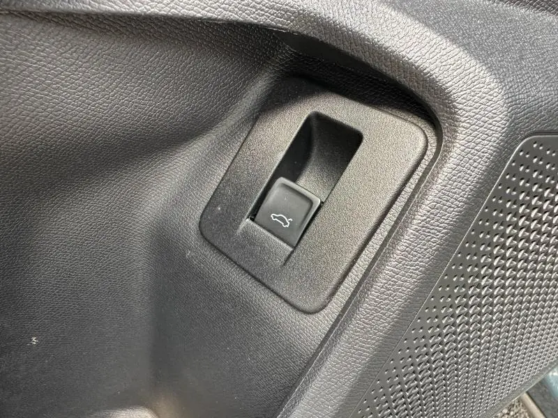 Bouton d'ouverture électrique du coffre sur panneau intérieur noir texturé d'une CUPRA Formentor bleu 2025.