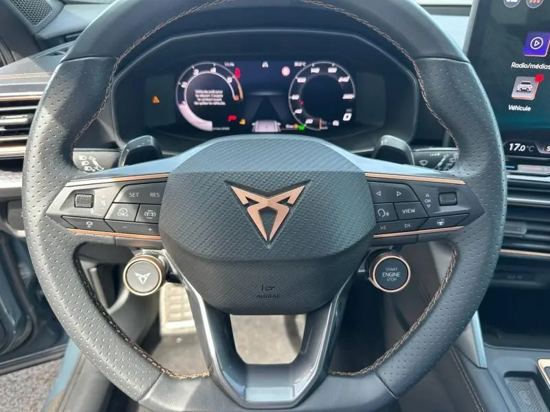 Vue rapprochée du volant cuir noir perforé avec logo CUPRA cuivre et commandes multifonctions du tableau de bord.