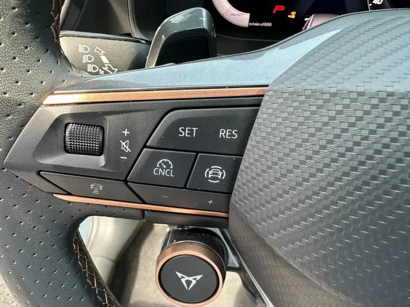 Gros plan sur les commandes du volant côté gauche du CUPRA Formentor bleu, avec bouton multifonction et finition carbone.