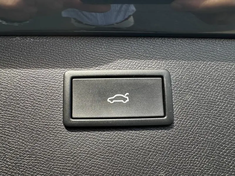 Bouton noir d'ouverture électrique du coffre sur tableau de bord texturé d'une CUPRA Formentor bleu 2025.