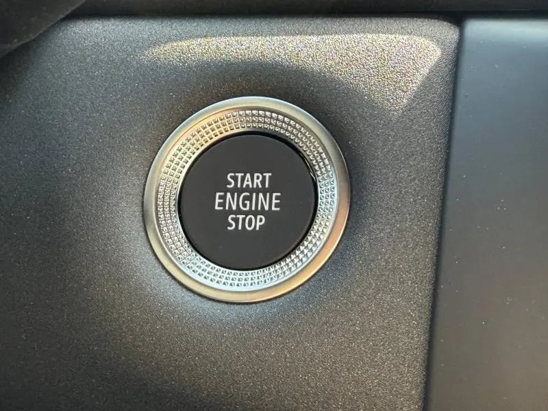 Gros plan sur le bouton Start Engine Stop entouré d'un anneau texturé dans l'habitacle du Renault Captur gris Rafale.