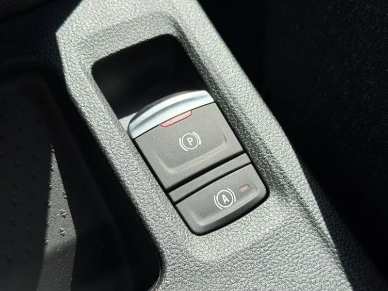 Gros plan sur les boutons de frein à main électronique et arrêt auto du moteur du Renault Captur gris Rafale.