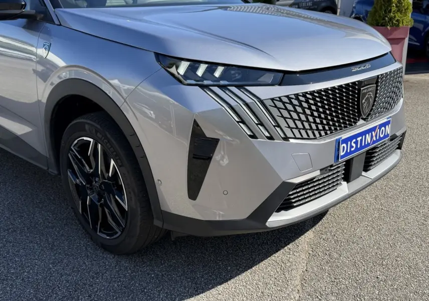 Peugeot 3008 gris clair en 3/4 avant droit, avec calandre distinctive et jantes noires brillantes.