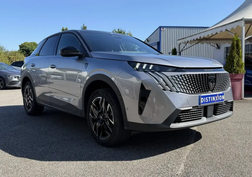 Vue 3/4 arrière droite d’un Peugeot 3008 gris clair hybride avec jantes noires et toit noir brillant.