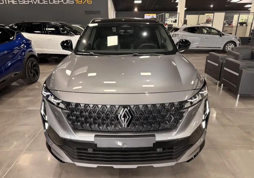 Vue avant d’un Renault Austral full hybrid gris schiste avec toit noir, calandre hexagonale et éclairage LED distinctif en showroom.