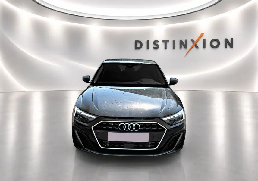 Vue avant d'une Audi A1 Sportback noire 2026 avec calandre hexagonale et phares LED dans un showroom lumineux.