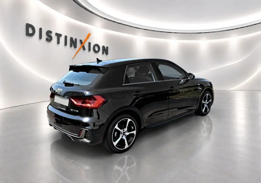 Audi A1 Sportback noir vue 3/4 arrière droit dans un showroom avec jantes alu et becquet arrière.