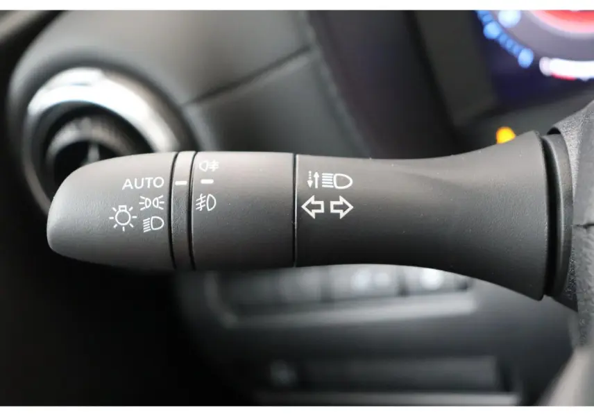 Gros plan sur la commande des feux et clignotants dans l'habitacle du Nissan Juke hybride 2026.