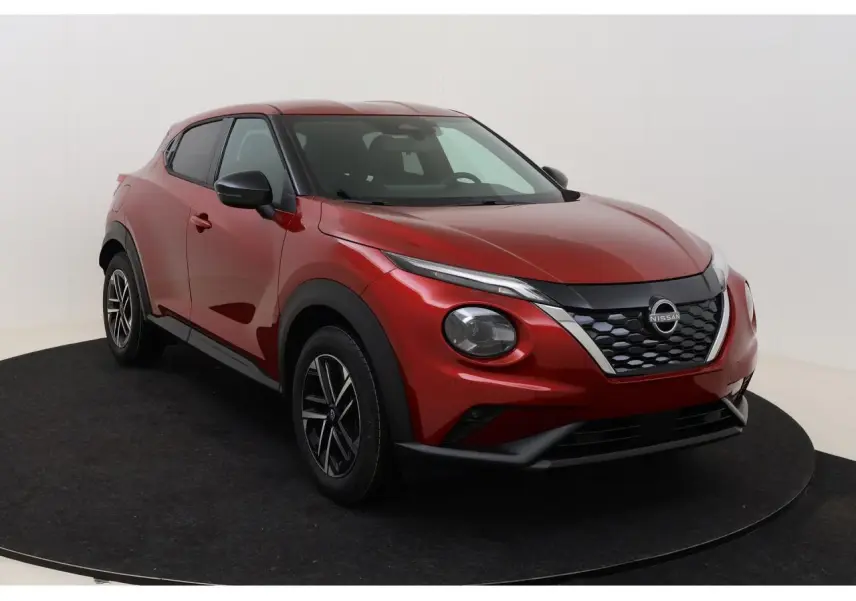 Nissan Juke rouge Fuji Sunset en 3/4 avant droit, avec calandre noire et jantes alliage 17 pouces.