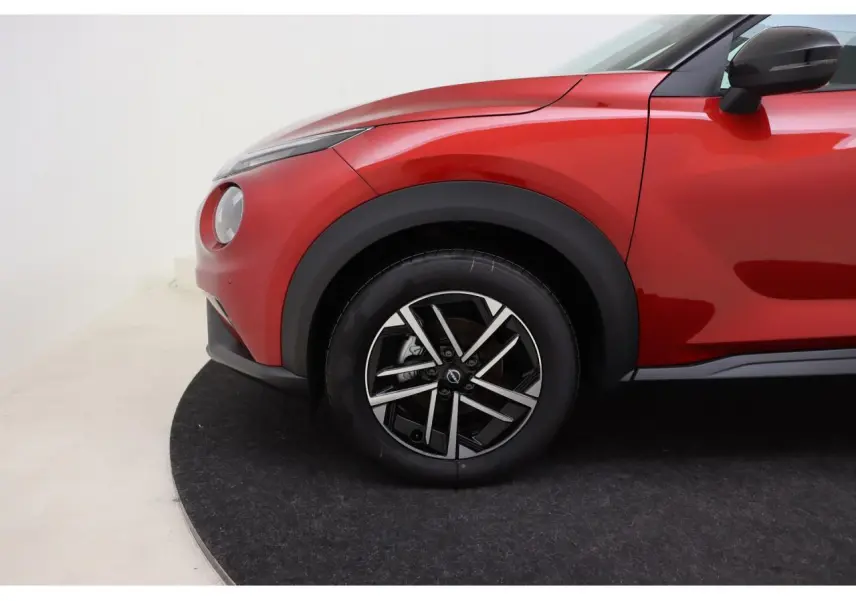 Gros plan sur la roue avant gauche et l'aile rouge Fuji Sunset du Nissan Juke 2026 avec jante alliage 17 pouces.