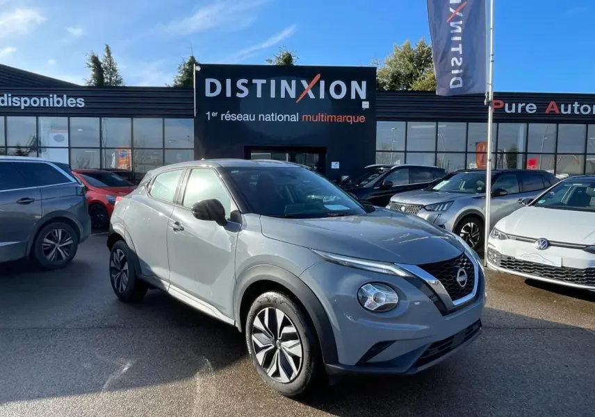 Nissan Juke II gris ceramic en 3/4 avant droit, avec jantes alliage noires et calandre V-motion distinctive.