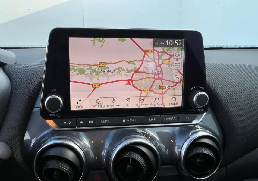 Écran tactile central avec navigation affichée et commandes rondes d’aération sur tableau de bord gris métallisé du Nissan Juke 2024.