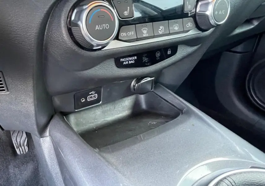 Détail de la console centrale noire du Nissan Juke 2024 avec commandes climatisation et ports USB visibles