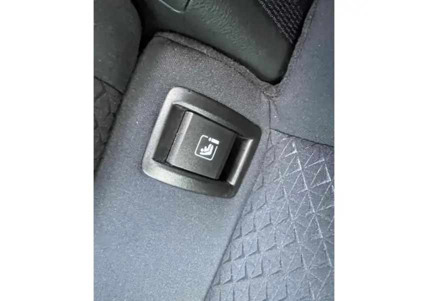 Gros plan sur le bouton de rabattement de siège arrière sur la banquette tissu gris du Nissan Juke II 2024.