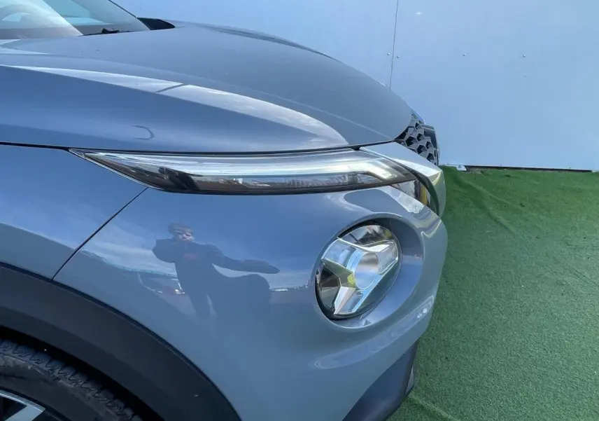 Gros plan sur l'avant droit du Nissan Juke 2024 gris ceramic, mettant en valeur son phare rond et sa calandre distinctive.