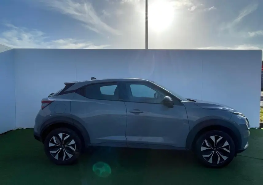 Profil côté gauche du Nissan Juke II 1.0 DIG-T 114 Tekna 2024 en gris ceramic avec jantes alliage noires.