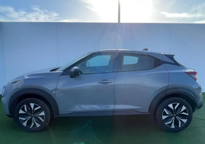 Profil côté gauche du Nissan Juke II gris ceramic 2024 avec jantes alliage noires et coques de rétroviseurs assorties.