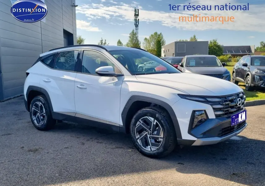Vue 3/4 avant du Hyundai Tucson blanc atlas avec calandre grise et jantes alliage 17 pouces.
